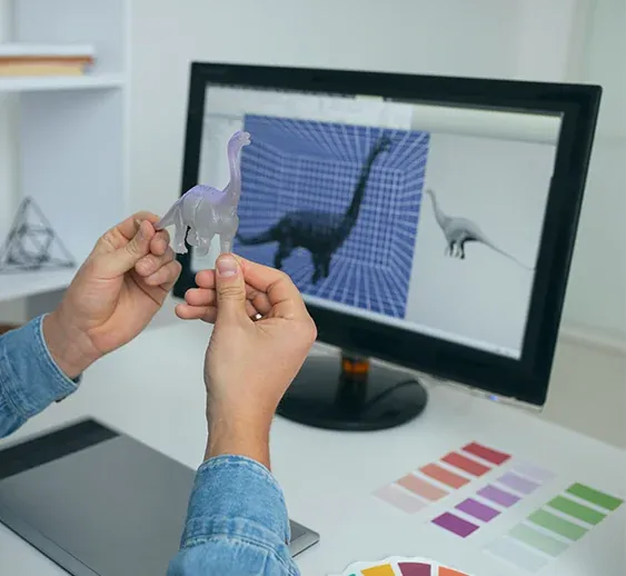 Mains tenant une figurine de dinosaure devant un écran de modélisation 3D en studio