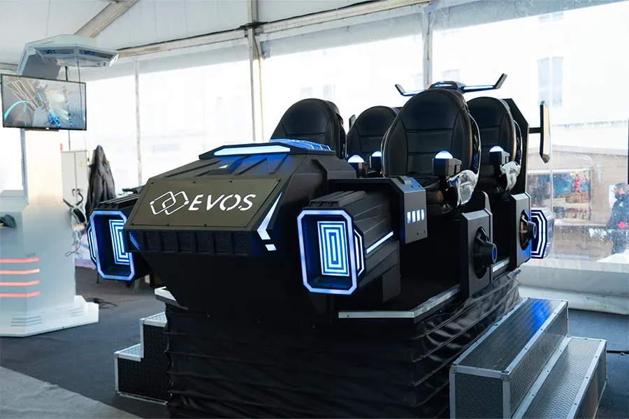 Simulateur navette VR Evos noir à quatre sièges avec logo Evos visible installé dans un espace vitré avec baies et sol bleu