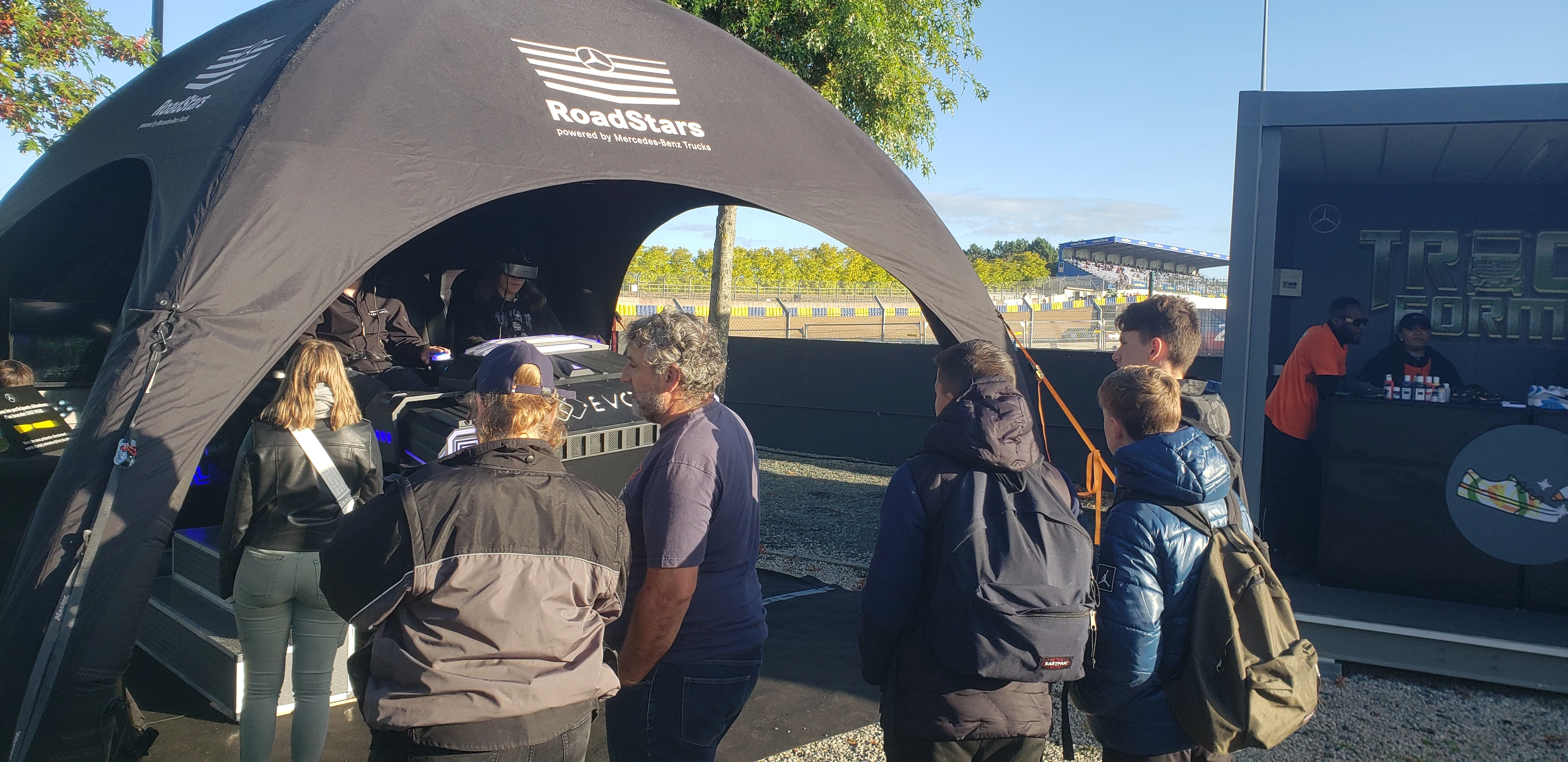 File d'attente grand public devant le simulateur sous tente avec tribunes du circuit Bugatti