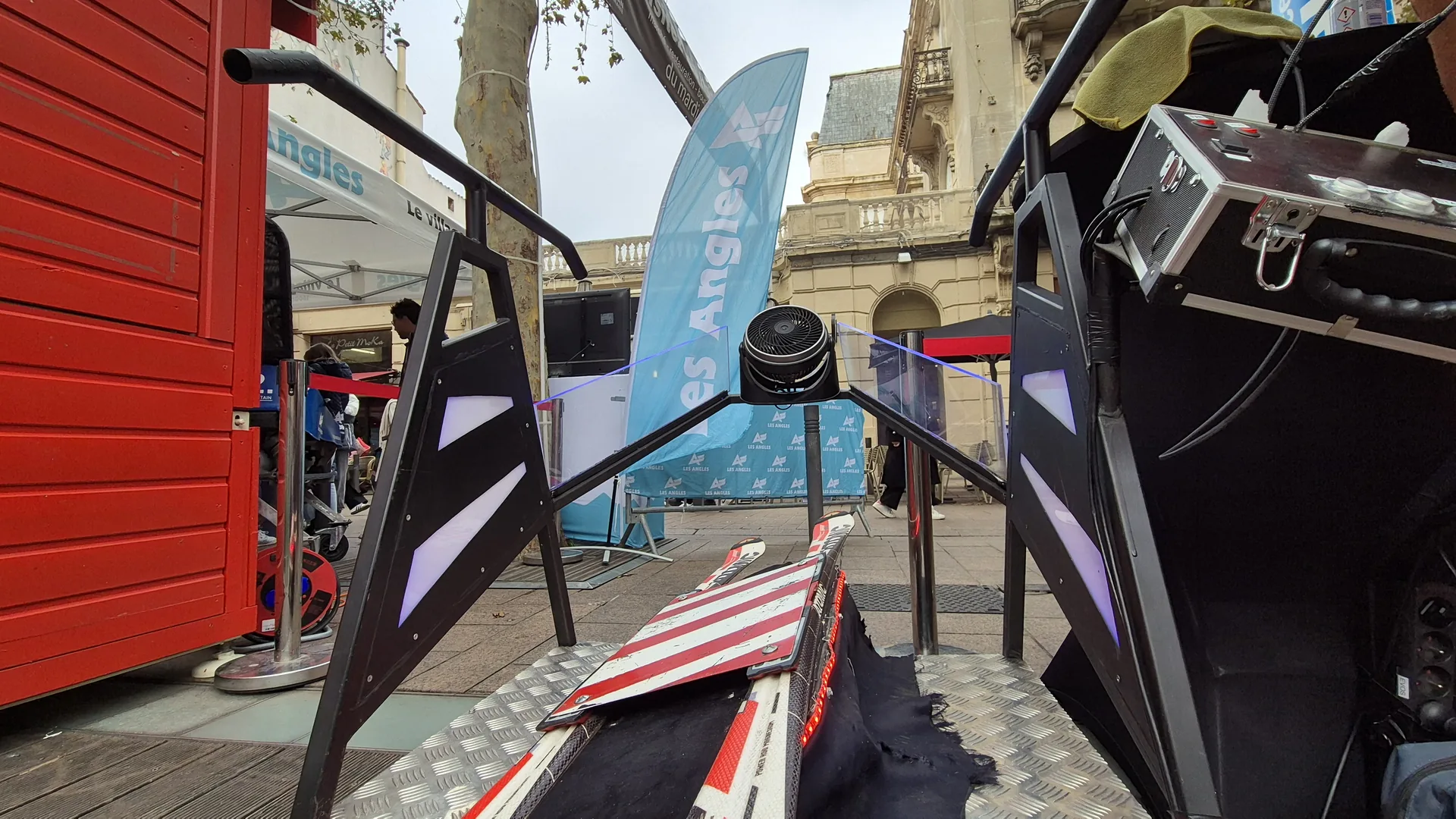 Simulateur ski VR à côté d'une oriflamme bleue Les Angles sur une place commerciale du centre de Perpignan
