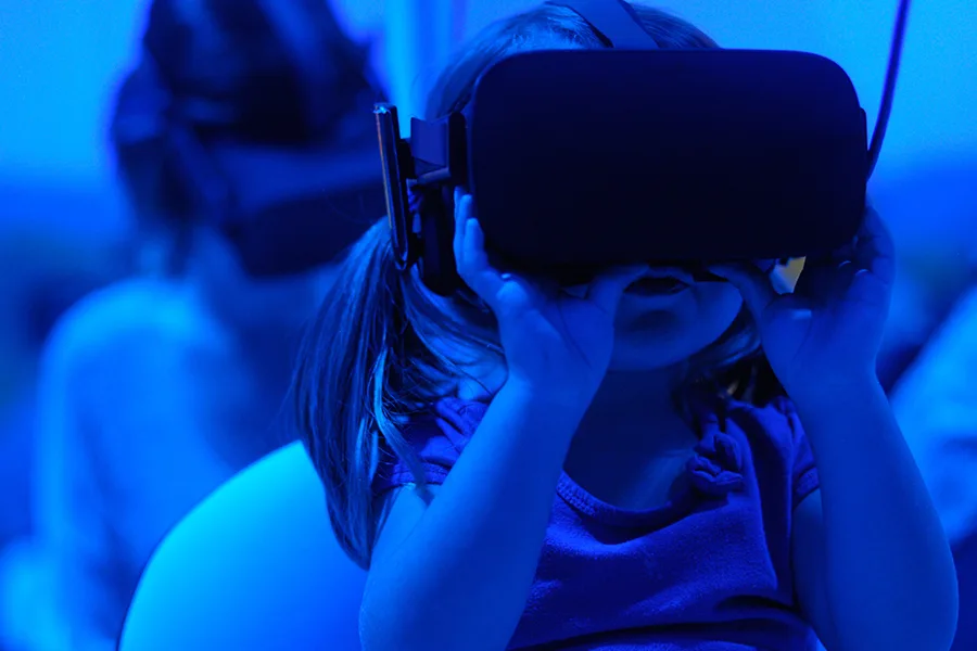Enfant portant un casque de réalité virtuelle sous un éclairage bleu