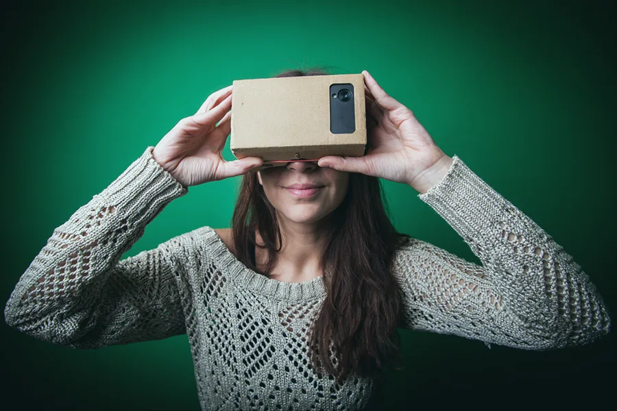 Personne tenant un Google Cardboard déplié devant son visage avec un smartphone inséré