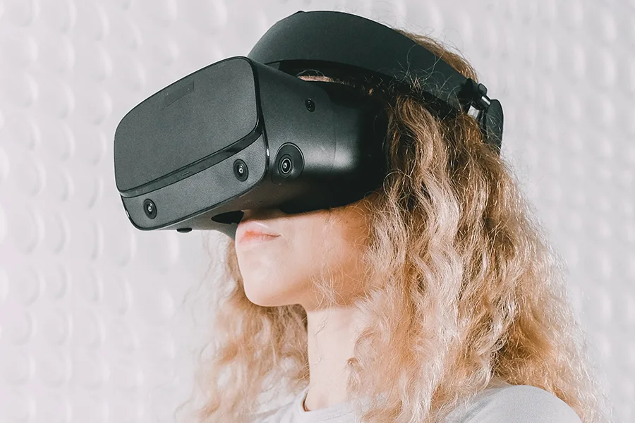 Femme aux cheveux bouclés portant un casque de réalité virtuelle noir vue de profil