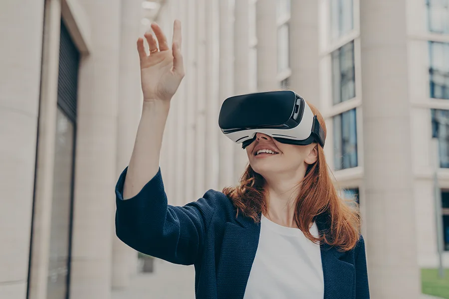 Femme en tailleur bleu portant un casque VR devant un bâtiment à colonnes