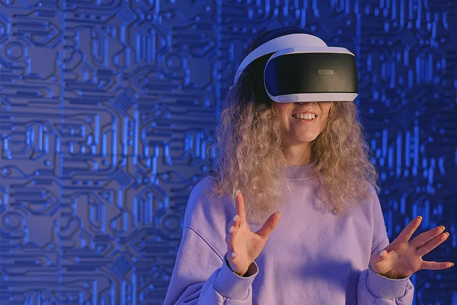Jeune femme avec casque VR blanc les mains ouvertes devant un décor numérique bleu