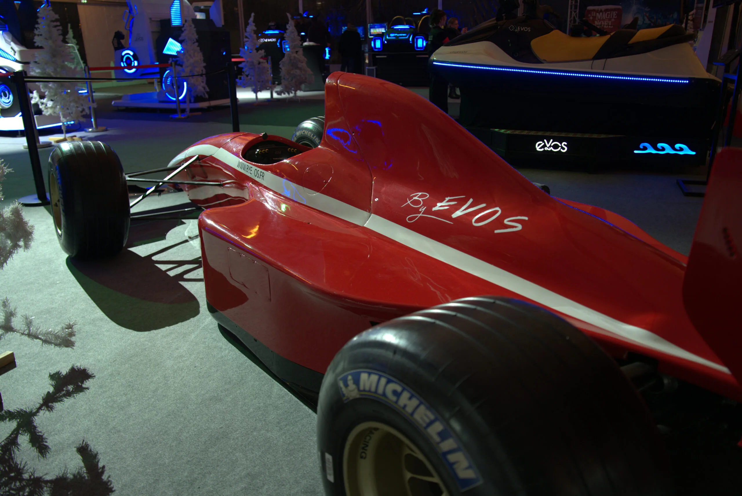 Simulateur Formule 1 rouge By Evos avec pneus Michelin dans un espace d'exposition