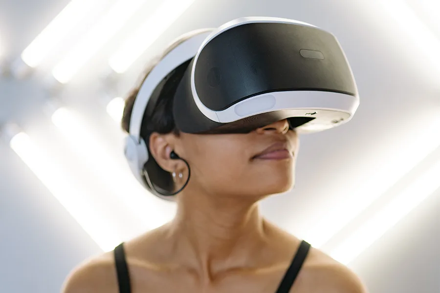 Femme souriante portant un casque VR blanc avec écouteurs sous un éclairage néon