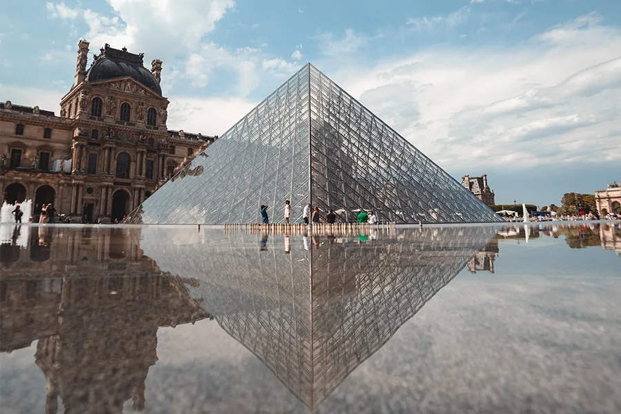 Pyramide du Louvre et son reflet dans le bassin avec la façade du palais en arrière-plan