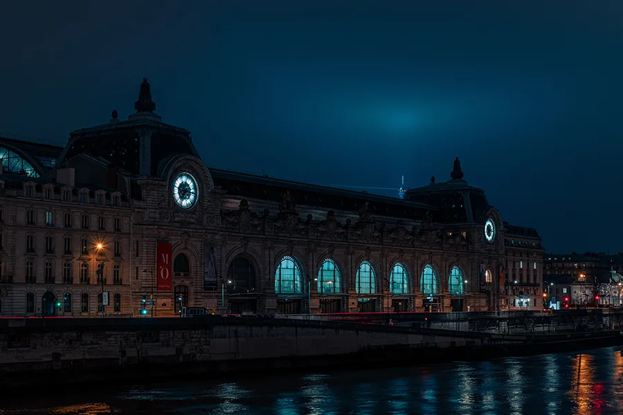 Façade du musée d'Orsay illuminée de nuit vue depuis les quais de Seine