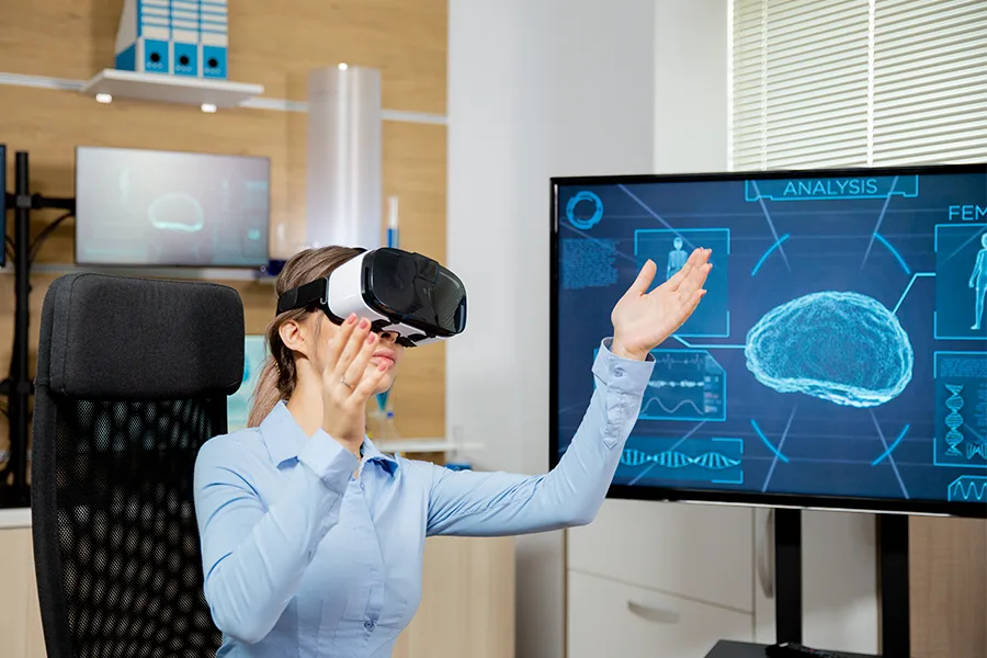 Professionnelle de santé portant un casque VR devant un moniteur affichant une imagerie cérébrale 3D