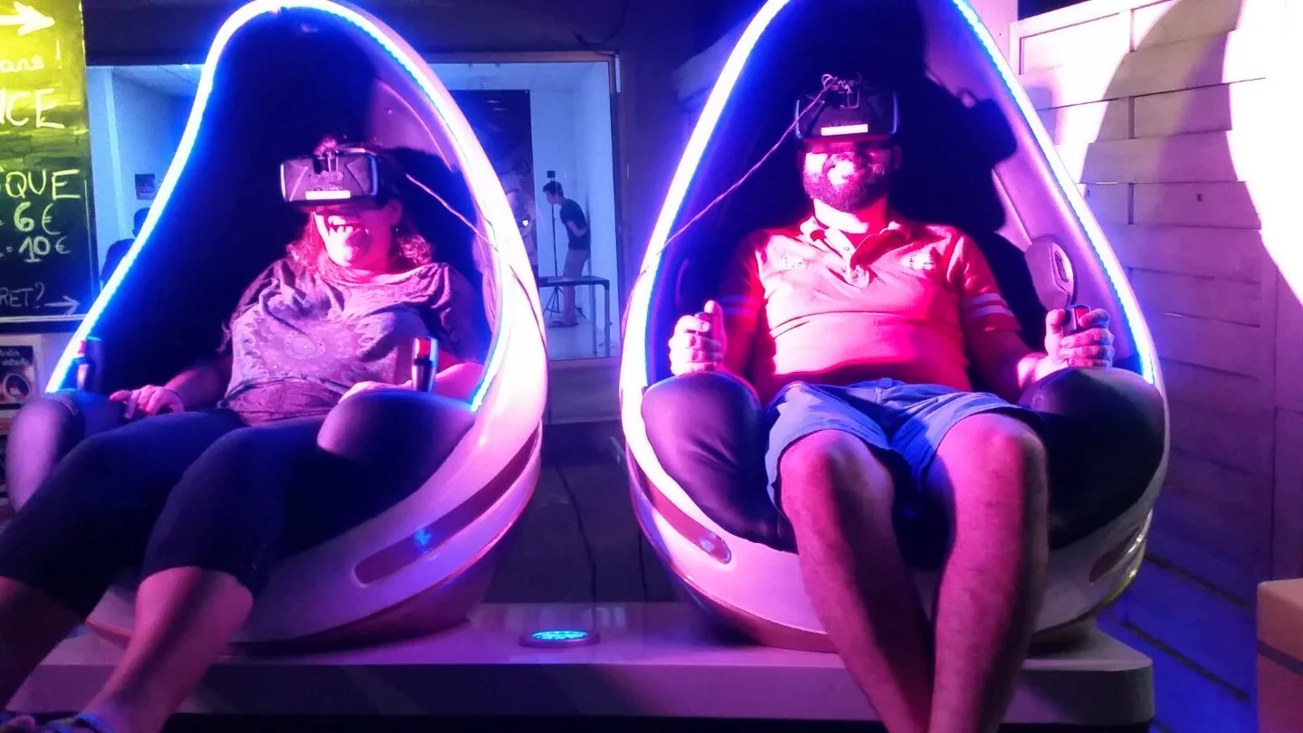 Couple en casque VR dans les fauteuils Evos Sensation sous éclairage rouge et bleu pendant une session de soirée