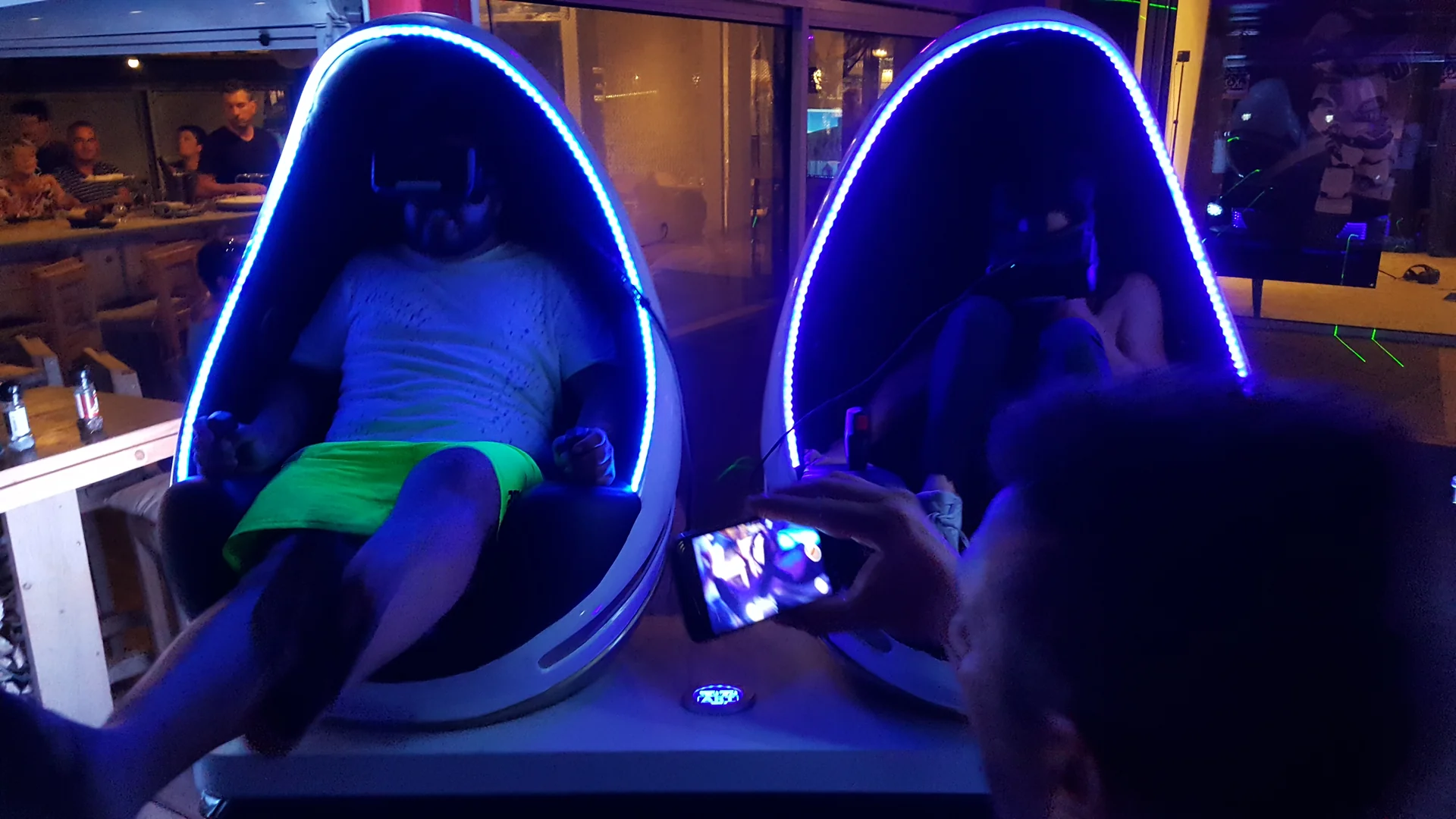 Deux participants assis dans les fauteuils Evos Sensation à LED bleues casques VR sur la tête pendant une session de nuit