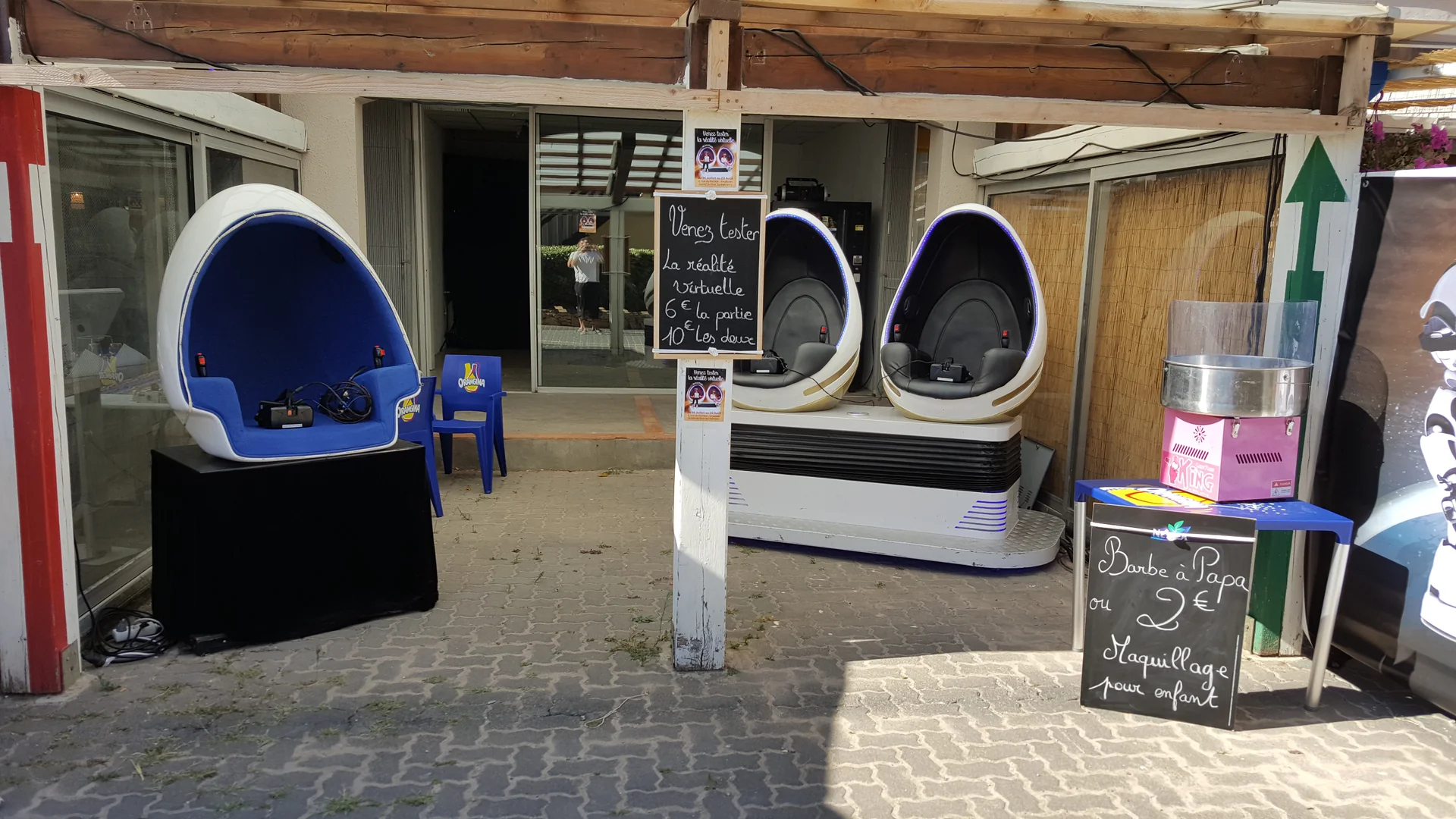 Stand vu de jour avec deux fauteuils Evos Sensation un Cocooning VR solo devant la vitrine et distributeur automatique