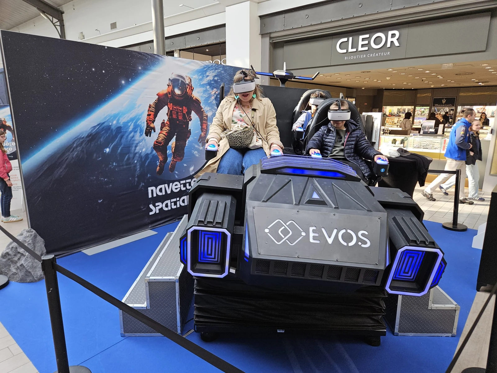 Simulateur navette VR 4 places en action devant fond astronaute géant à Aushopping Englos Les Géants