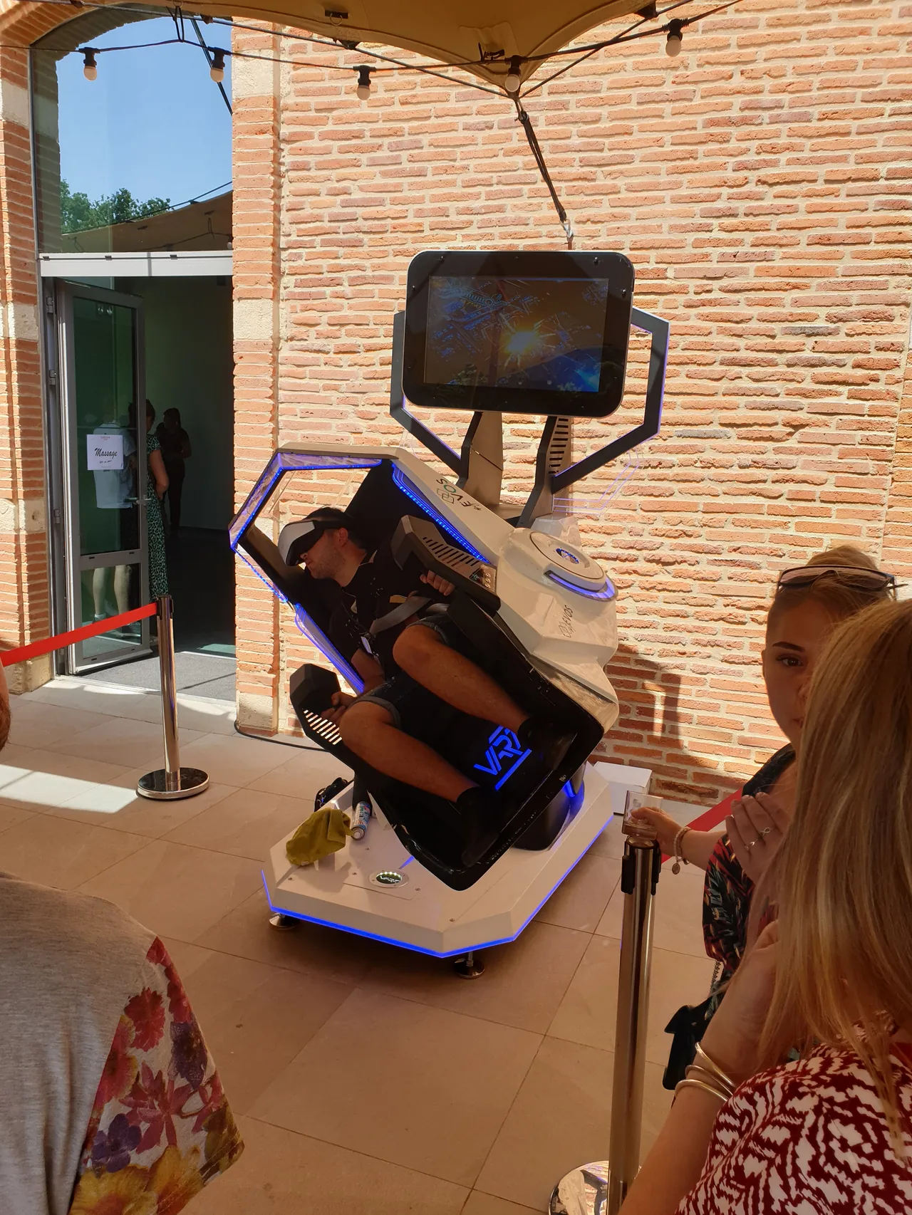 Participante casquée VR dans le simulateur SOL 2 places sous la terrasse en brique du Domaine de Preissac