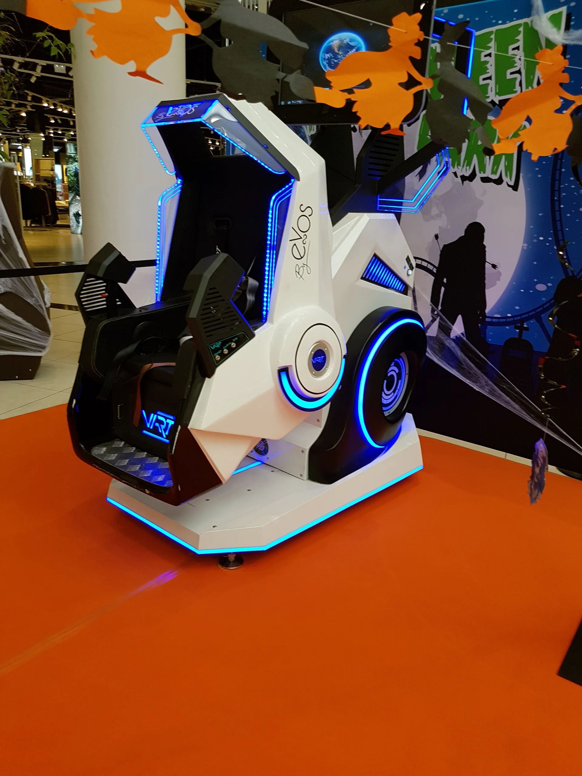 Vue rapprochée du simulateur SOL 360 VR avec rubans LED bleus et signature by Evos posé sur tapis orange Halloween