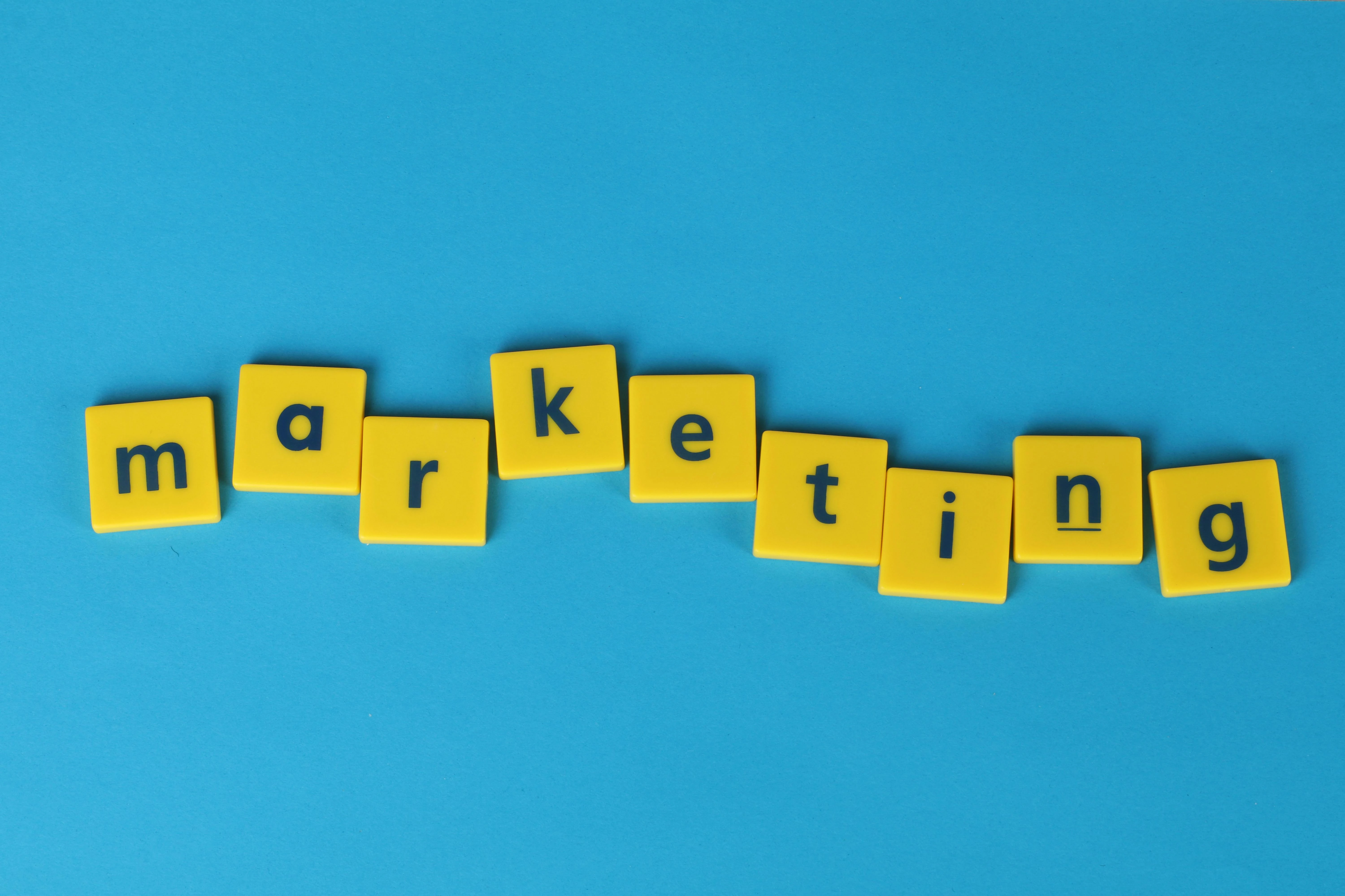 Tuiles de lettres jaunes épelant marketing sur fond bleu - stratégie de marketing immersif