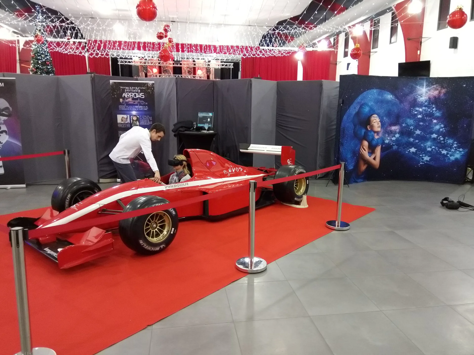 Animateurs encadrant le démarrage d'une session VR derrière le simulateur Formule 1 dans la salle des fêtes