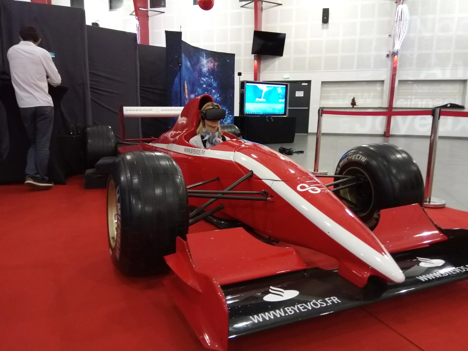 Participante casquée VR au volant du simulateur Formule 1 grandeur réelle pendant l'animation municipale