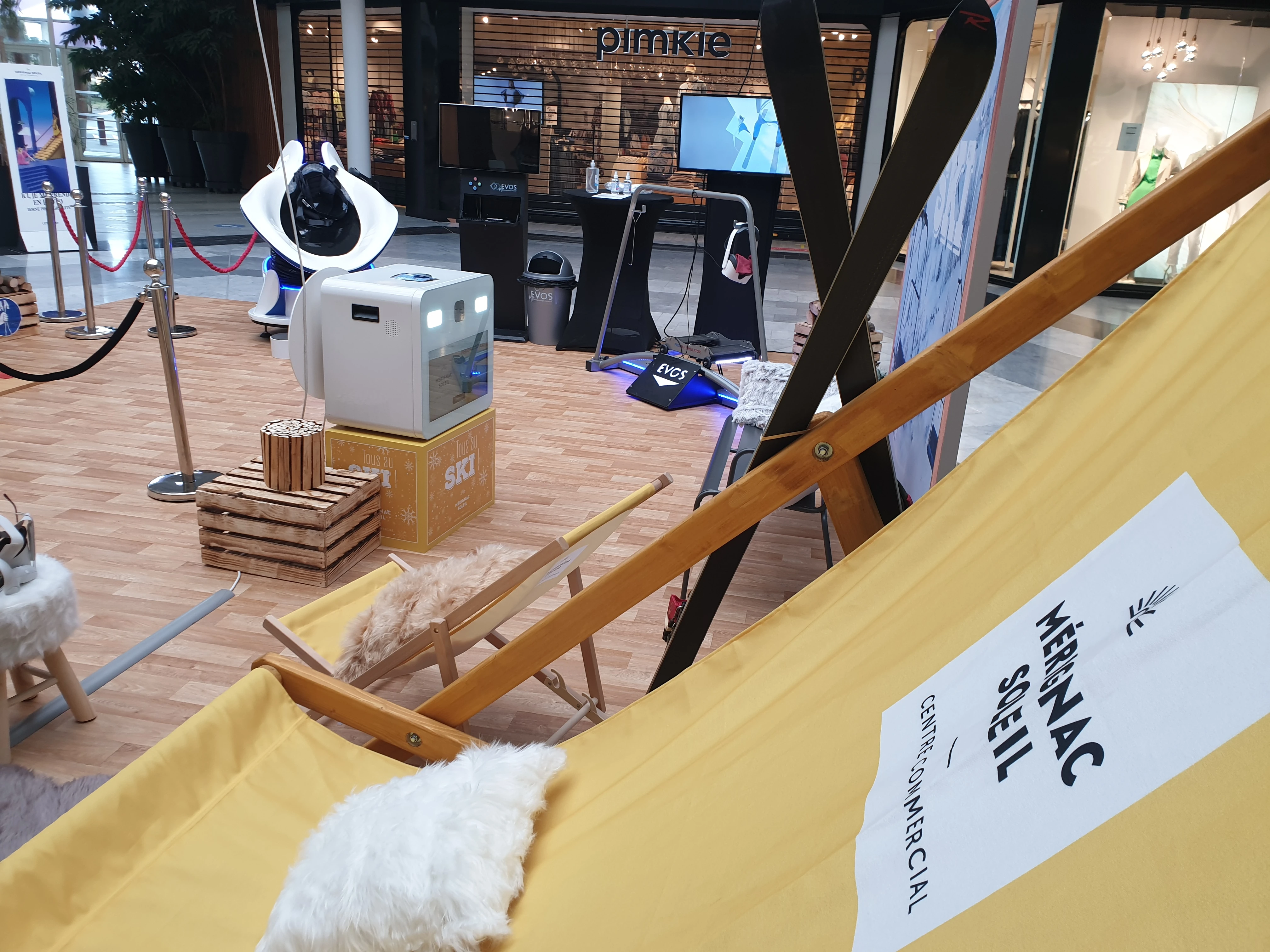 Tipi jaune avec logo Mérignac Soleil Centre Commercial et skis en bois adossés contre la toile