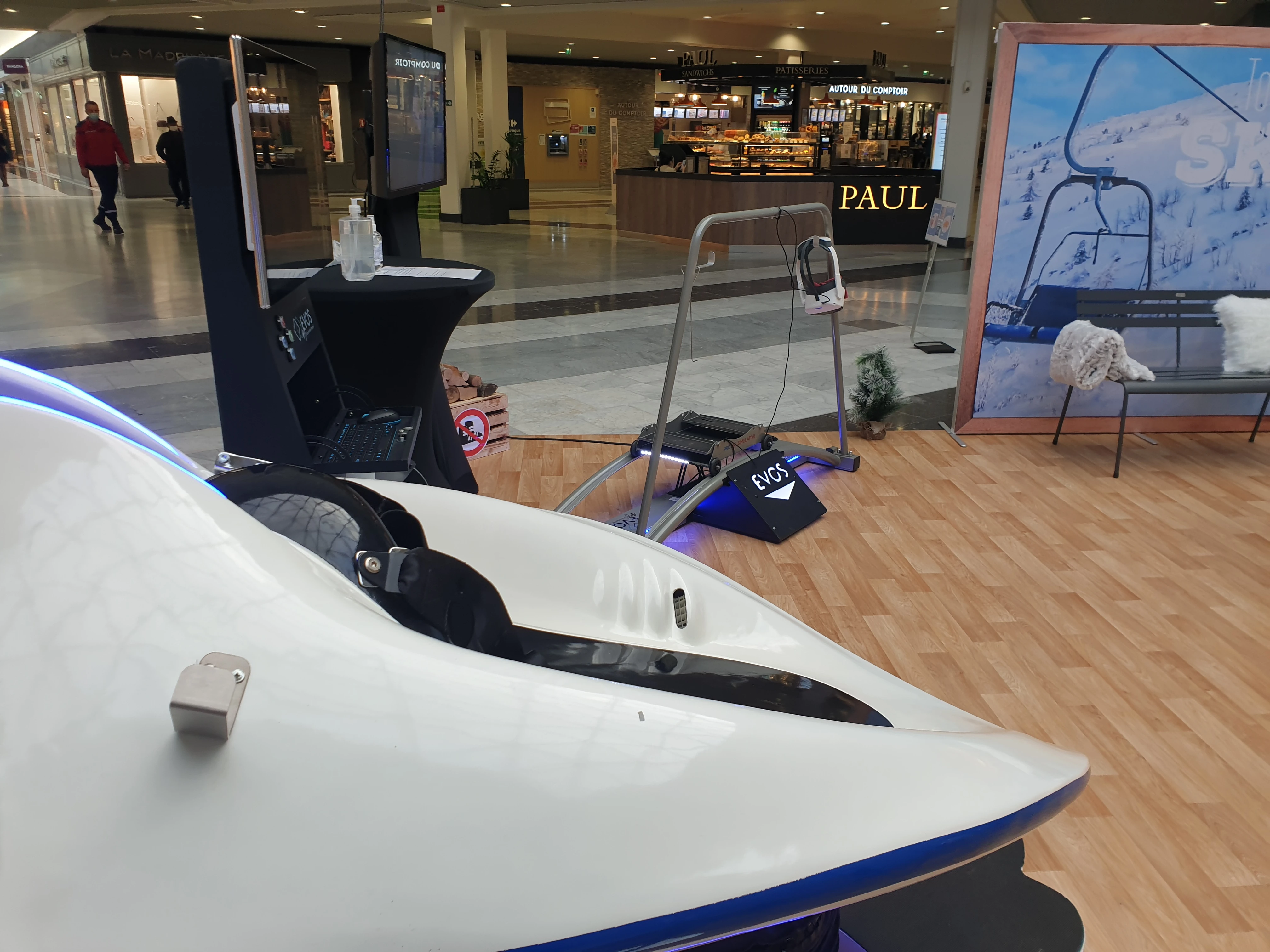Luge VR sur structure mécanique au premier plan et simulateur ski VR au fond face à la boulangerie PAUL