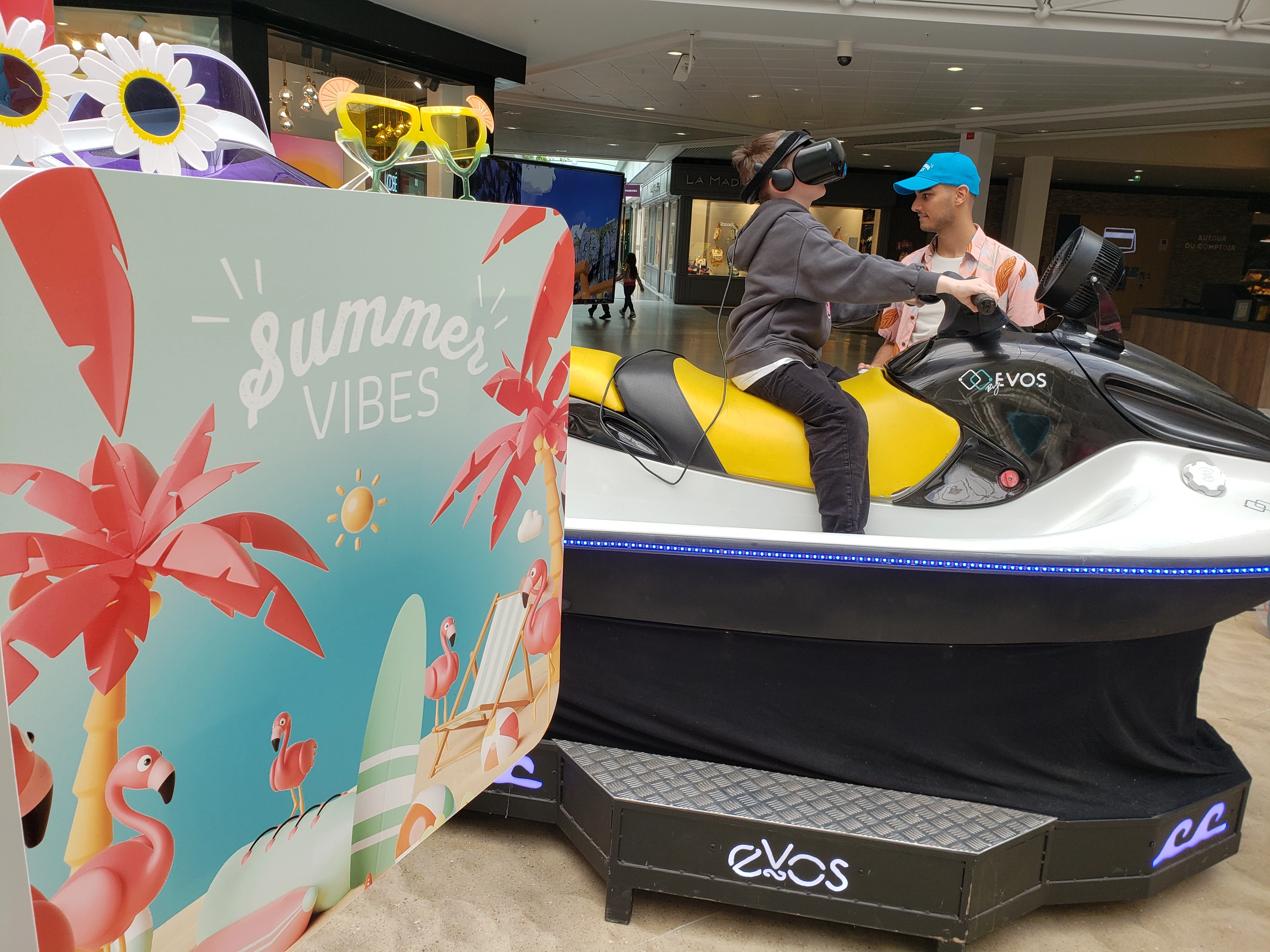 Visiteur casque VR sur le jet ski By Evos avec décor Summer Vibes palmiers et flamants roses