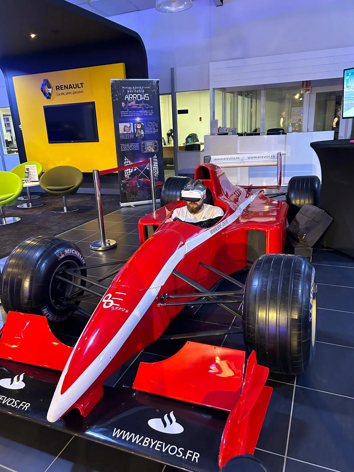 Simulateur F1 ARROWS rouge devant le panneau Renault dans le showroom d'Aurillac lors de la soirée de lancement