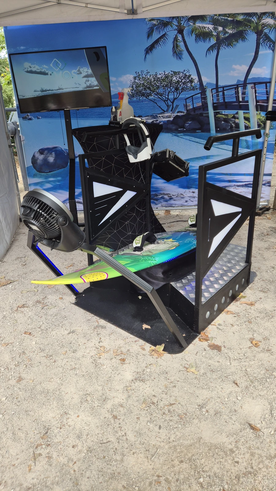 Setup du simulateur surf VR avec décor mural plage tropicale sous tente blanche extérieure