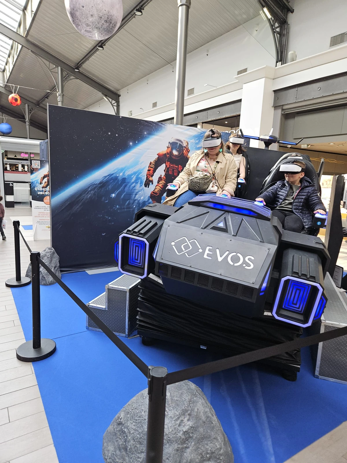 Vue rapprochée du simulateur navette VR 4 places branding EVOS bleu en galerie marchande Englos