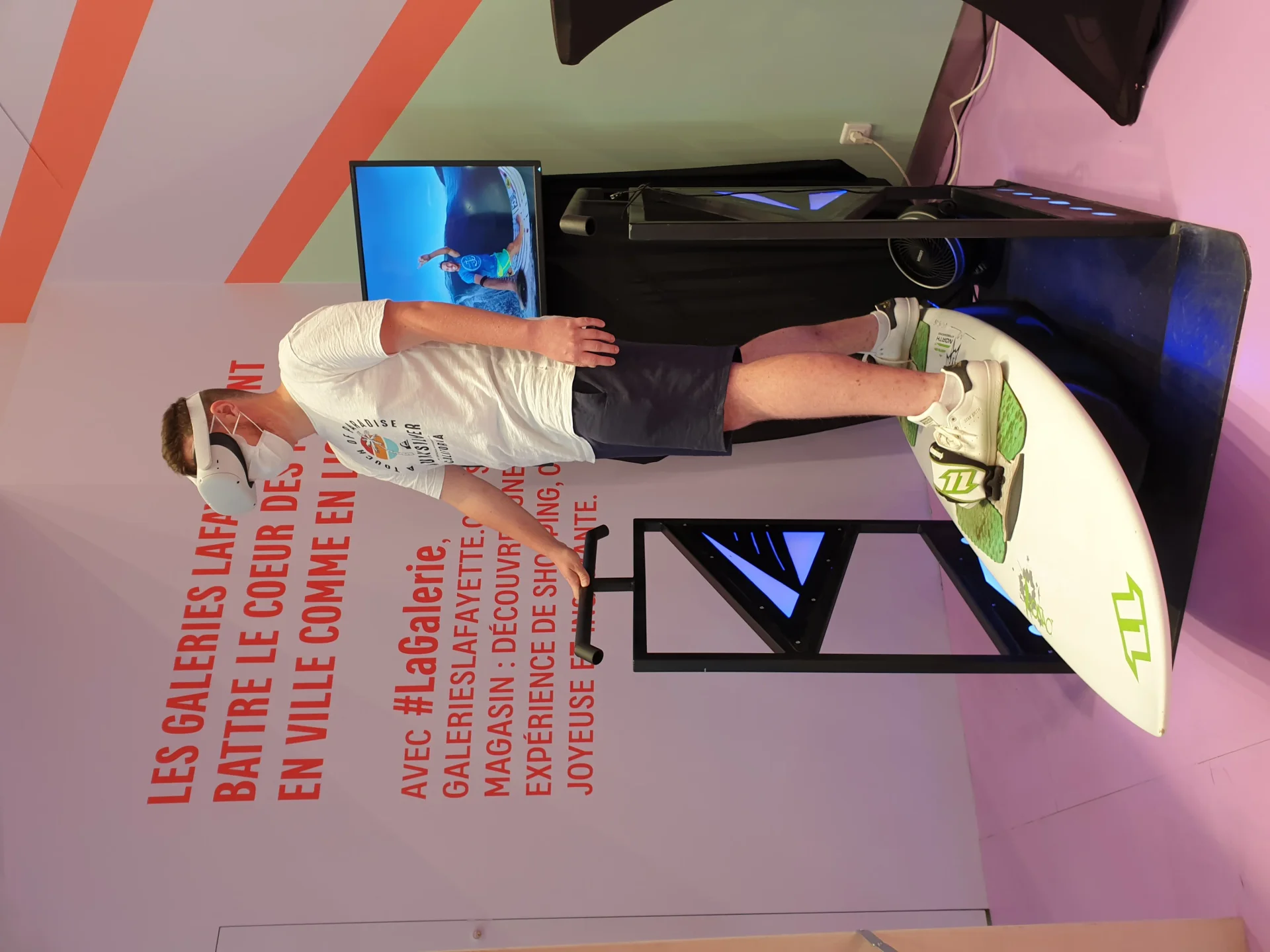 Participant en casque VR sur le simulateur de surf By Evos lors d'une animation aux Galeries Lafayette de Bordeaux