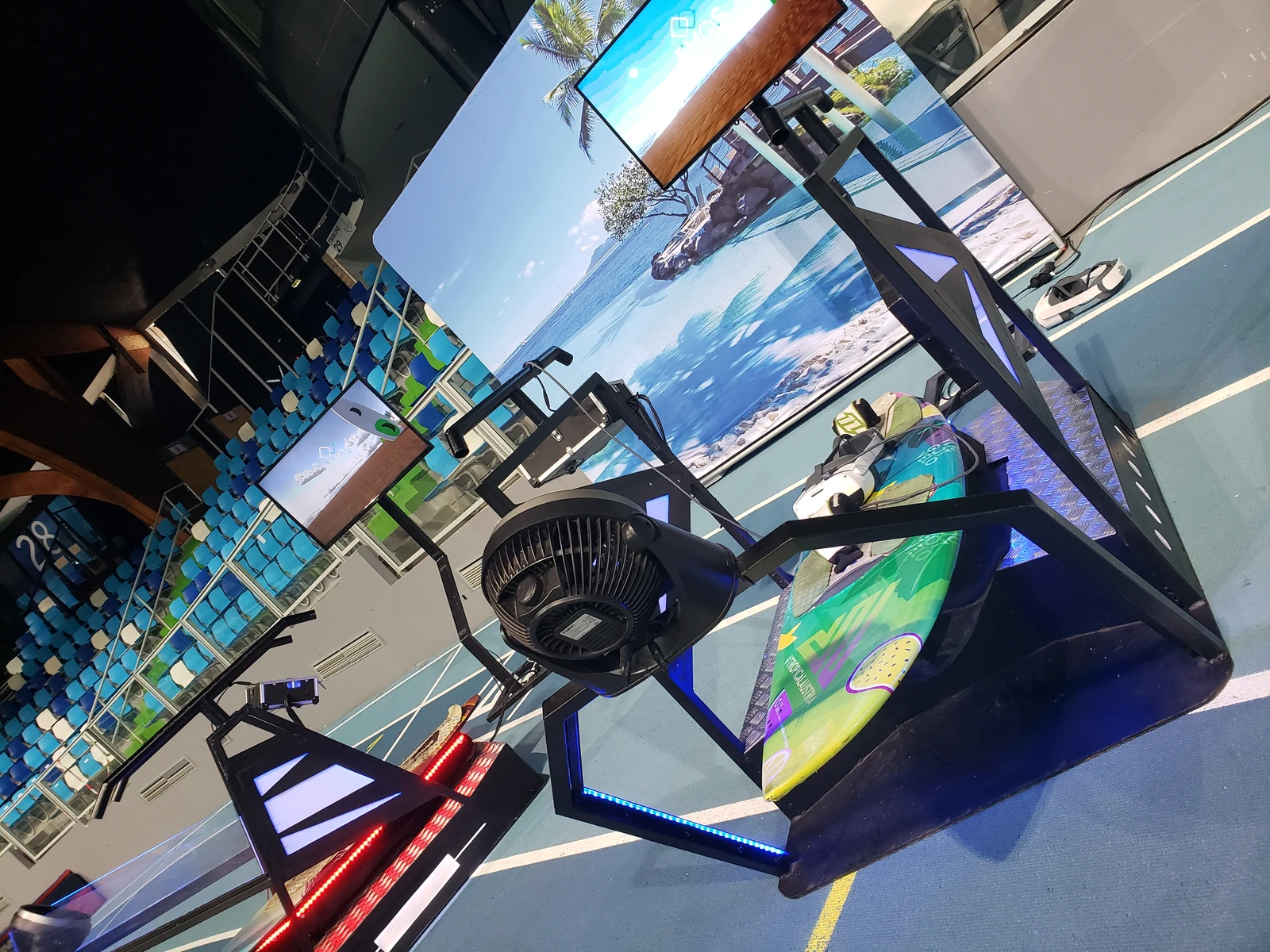 Simulateur surf VR avec planche flashy sur plateforme balance et écran TV diffusant la session