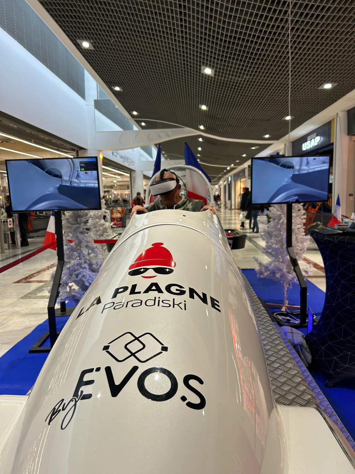 Visiteur en pleine session VR sur le simulateur bobsleigh aux couleurs La Plagne Paradiski en centre commercial