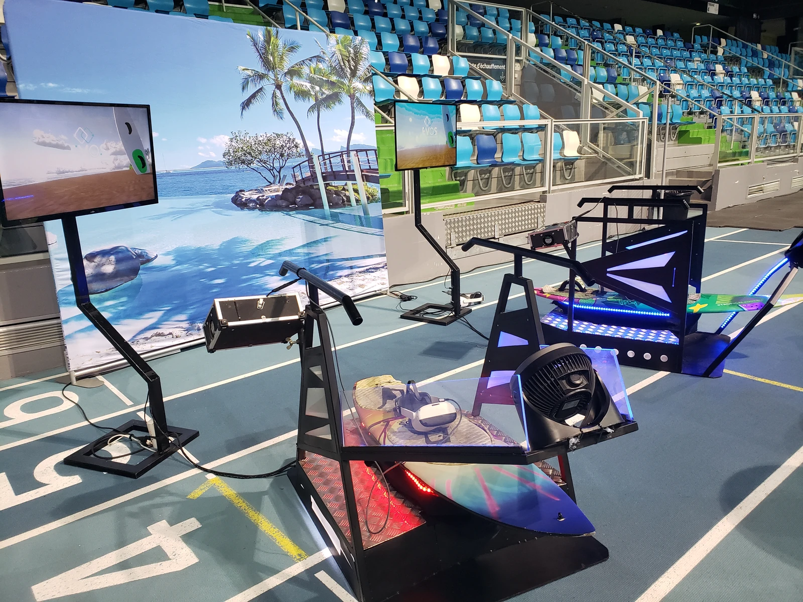 Vue large des deux simulateurs VR installés sur la piste athlétisme bleue de l'Arena Liévin avec gradins en arrière-plan