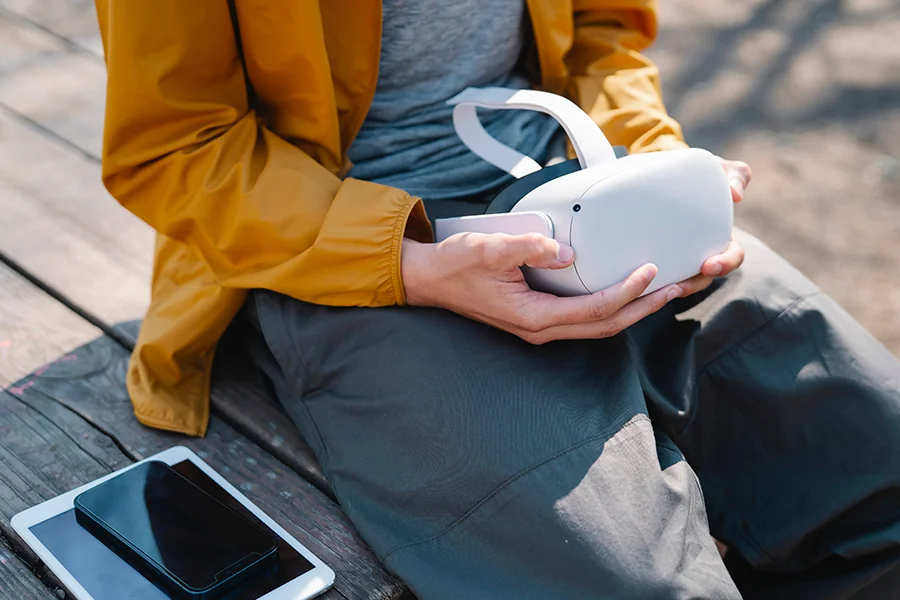 Personne assise avec un casque VR mobile et un smartphone posé à côté