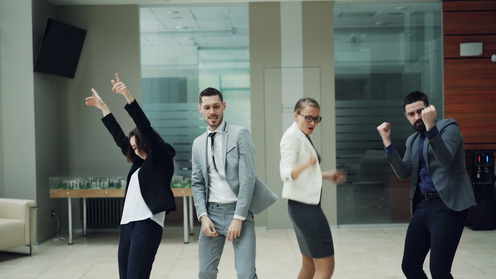 Quatre collaborateurs en costume dansent et lèvent les bras lors d'une soirée d'entreprise
