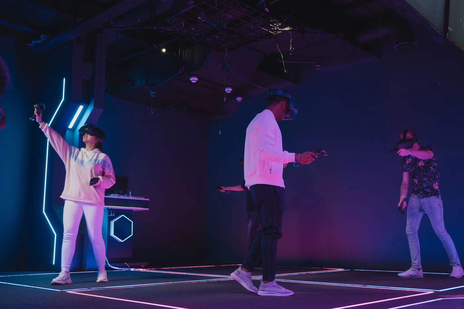 Trois participants casque VR et manettes en main dans une arène de jeu en salle éclairée aux LED