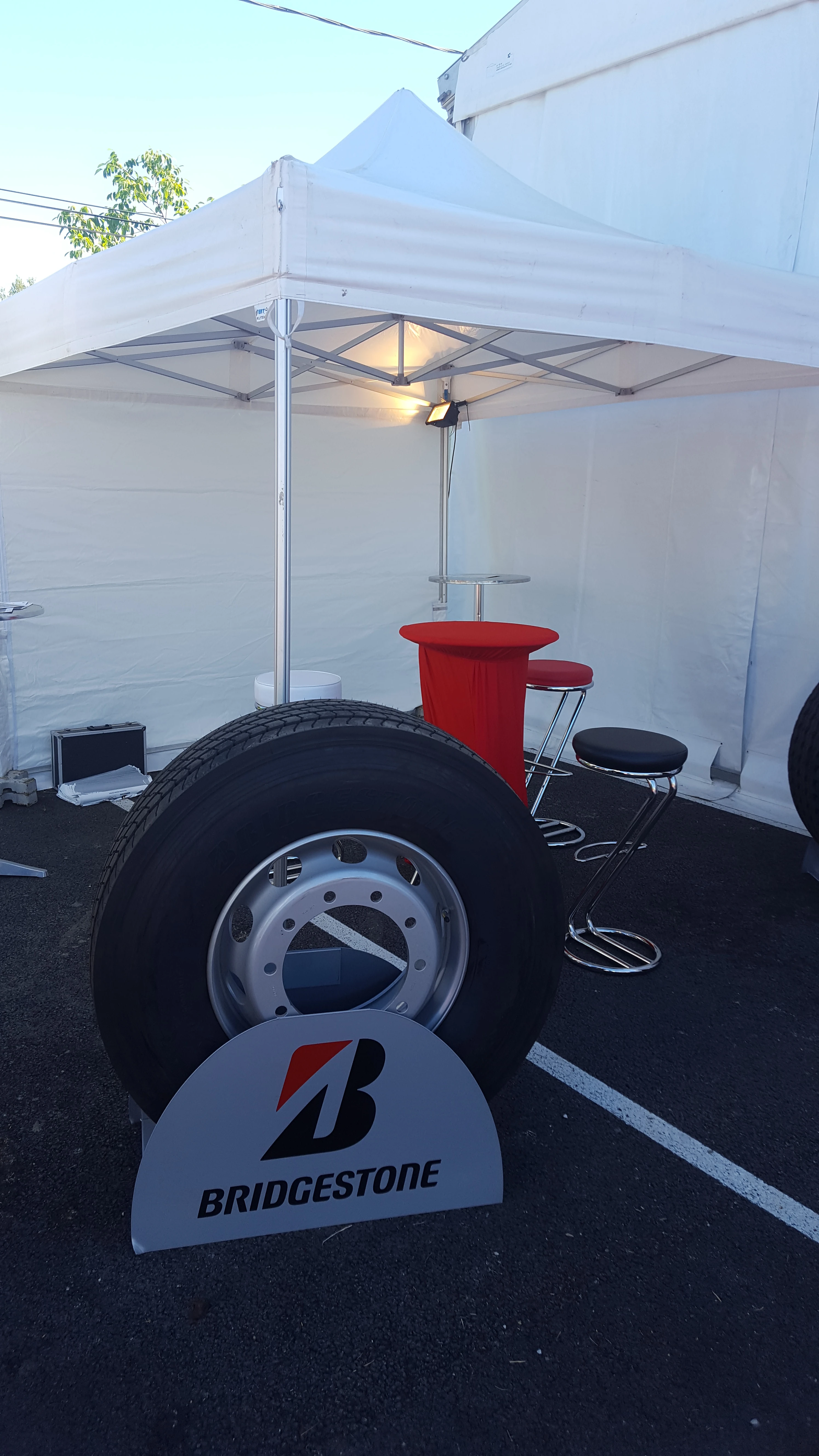 Stand partenaire Bridgestone avec pneu poids lourd exposé sous chapiteau lors de l'inauguration Transports Sarrazain