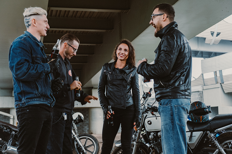 Groupe de 3 hommes et une femme, vêtus de vestes en cuir, discutant avant une balade à moto lors d'une journée d'entreprise