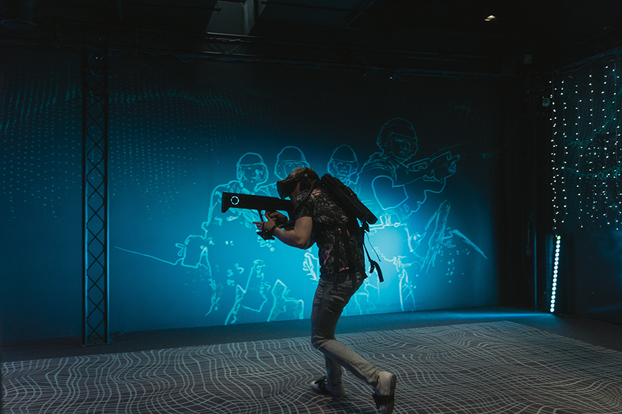 Un jeune homme tenant une mitraillette de réalité virtuelle dans une salle de jeu