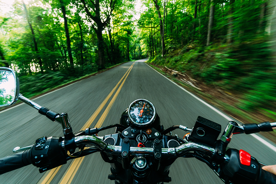 Moto conduite sur une route forestière ombragée par un motard hors-champ
