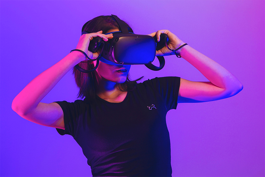 une femme qui porte un casque de réalité virtuelle devant un fond violet